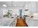 Bright kitchen with white cabinets, stainless steel appliances, and a large island with a marble countertop and hardwood floors at 325 Forest Bridge Rd, Youngsville, NC 27596