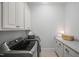 Well-lit laundry room features modern gray washer and dryer, granite countertops, and ample storage at 325 Forest Bridge Rd, Youngsville, NC 27596