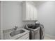 Functional laundry room with modern washer and dryer units, sink, and upper cabinets at 325 Forest Bridge Rd, Youngsville, NC 27596