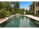 A luxury swimming pool in the backyard featuring travertine, fire bowls, and lounge chairs at 325 Forest Bridge Rd, Youngsville, NC 27596