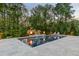 In-ground pool with tanning ledge, surrounded by mature trees and landscaping, and fire bowls at 325 Forest Bridge Rd, Youngsville, NC 27596