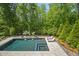 Aerial view of a backyard in-ground pool and tanning deck surrounded by mature trees and foliage at 325 Forest Bridge Rd, Youngsville, NC 27596