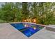 Outdoor pool with tanning ledge, surrounded by mature trees and landscaping, and illuminated fire bowls at 325 Forest Bridge Rd, Youngsville, NC 27596