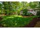 Spacious backyard with mature trees and lush landscaping and a view of screened in porch at 3804 Nottaway Rd, Durham, NC 27707