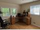 Bright home office features a large L-shaped desk, hardwood floors, and green outdoor views at 5002 Wickham Rd, Raleigh, NC 27606