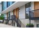 Modern townhome entrance with light gray siding, wood doors, and black metal stairs at 511 S Bloodworth St # 102, Raleigh, NC 27601