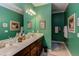 Well-lit bathroom featuring double sinks, a dark vanity, green walls, and decorative artwork at 5144 Niagra Dr, Chapel Hill, NC 27517