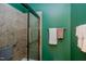Tiled shower with glass door in a bathroom with green walls and towel racks at 5144 Niagra Dr, Chapel Hill, NC 27517