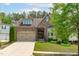 Charming stone home features a manicured lawn, two-car garage, and covered front porch at 525 Morning Oaks Dr, Holly Springs, NC 27540