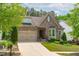 Charming stone home features a manicured lawn, two-car garage, and covered front porch at 525 Morning Oaks Dr, Holly Springs, NC 27540