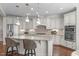 Spacious kitchen with white cabinets, granite countertops, stainless steel appliances and a large island with barstool seating at 525 Morning Oaks Dr, Holly Springs, NC 27540