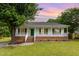 Charming single-story home with a welcoming front porch and manicured lawn at sunset at 5317 Cottage Bluff Ln, Knightdale, NC 27545
