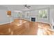 Open living room with hardwood floors, fireplace, ceiling fan, and access to additional spaces at 5705 Tannibark Ln, Fuquay Varina, NC 27526