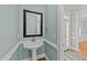 Charming powder room with pedestal sink, decorative mirror, and fresh, light blue walls at 5705 Tannibark Ln, Fuquay Varina, NC 27526