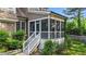 A cozy screened-in porch with white railings, accessible by stairs, surrounded by lush greenery at 5705 Tannibark Ln, Fuquay Varina, NC 27526