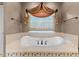 Close-up of the bathroom featuring a soaking tub with decorative tile surround and window at 7212 Donneeford Rd, Wake Forest, NC 27587