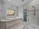 Bright bathroom boasts a soaking tub with marble surround and a glass enclosed shower at 7212 Donneeford Rd, Wake Forest, NC 27587
