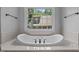 Bright bathroom features a luxurious soaking tub under a large window with black hardware at 7212 Donneeford Rd, Wake Forest, NC 27587