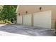 Three-car garage with traditional doors and exterior sconce lighting on a sunny day at 7212 Donneeford Rd, Wake Forest, NC 27587