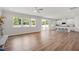 Open-concept living room with wood floors, many windows and white kitchen with island and seating at 73 Windswept Way, Fuquay Varina, NC 27526