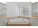 Well-lit bathroom featuring a tiled corner tub, vanity with double sinks, and a large window at 9117 Meadow Mist Ct, Raleigh, NC 27617