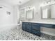 Bright bathroom featuring gray-tone mosaic tile floor and blue vanity with double mirrors and white countertop at 915 Edgewater Cir, Chapel Hill, NC 27516