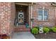 Inviting front porch with brick steps, flowerpots and decorative welcome sign at 928 Arrowhead Ln, Mebane, NC 27302