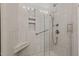Sleek tiled shower with glass door, recessed shelving, a seating area, and support bars at 928 Arrowhead Ln, Mebane, NC 27302