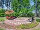 Inviting brick fire pit area with lounge chairs, umbrella, and garden at 948 Uprock Dr, Cary, NC 27519