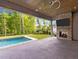 A covered patio features a stone fireplace, TV, ceiling fan and a beautiful view of the backyard pool at 949 Harrison Ridge Rd, Wake Forest, NC 27587