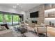 Open living room with stone fireplace, large TV, chandelier lighting, and view of the outdoor pool at 949 Harrison Ridge Rd, Wake Forest, NC 27587