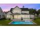 Rear view of home at dusk with a backyard pool, patio, and built in grill surrounded by green grass at 949 Harrison Ridge Rd, Wake Forest, NC 27587