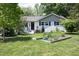 View of front yard with garden, white painted brick home and nice landscaping at 1004 Greenwich St, Raleigh, NC 27610