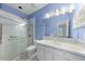 Well-lit blue bathroom with glass shower, grab bars, and a vanity with floral accents at 101 Abbotsford Ct, Durham, NC 27712