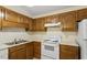 Practical kitchen with wood cabinetry and a white range and refrigerator at 101 Pickett Ln, Cary, NC 27511