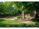 Lush backyard featuring mature trees, a winding stone path, and neatly mulched garden beds, creating a serene outdoor space at 101 Worsham Dr, Chapel Hill, NC 27516