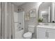 Well-lit bathroom featuring a shower-tub, toilet, and vanity with decoratively framed botanical art prints at 1100 Pecan Pl, Durham, NC 27704