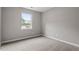 A bright bedroom with neutral carpeting, gray walls, and a large window offering great natural light at 1100 Pecan Pl, Durham, NC 27704