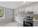 Well-lit kitchen features white cabinets, stainless steel oven range, and access to the backyard at 1100 Pecan Pl, Durham, NC 27704