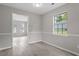 Bright living room featuring gray walls, laminate flooring, and a large window letting in natural light at 1100 Pecan Pl, Durham, NC 27704