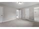 Large bedroom with neutral carpet, light gray walls, and multiple doorways and closets at 1100 Pecan Pl, Durham, NC 27704