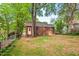 View of the back of a brick home and spacious backyard with grass and foliage at 1113 Alabama Ave, Durham, NC 27705