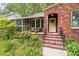 Close up of the brick home with a well-manicured lawn, and a cozy screened-in porch at 1113 Alabama Ave, Durham, NC 27705