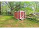 Red storage shed with white trim situated in a wooded backyard and chain link fence at 1113 Alabama Ave, Durham, NC 27705