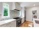 Clean kitchen with stainless steel oven and hood, gray cabinetry, and bright natural light from the window at 112 Meadowbrook Dr, Chapel Hill, NC 27514