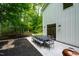 Outdoor dining set on a modern patio with a grill, near a white house and lush greenery at 112 Meadowbrook Dr, Chapel Hill, NC 27514