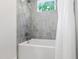 Bathtub and shower combo tiled in gray with window above the tub at 112 Meadowbrook Dr, Chapel Hill, NC 27514