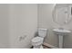 Well-lit half bathroom with a pedestal sink, toilet, and modern fixtures at 124 Myatt Fern Dr, Garner, NC 27529