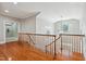 Hallway overlooking foyer with hardwood floors, natural light, and wooden banister, ideal for relaxation and enjoying the natural light at 12428 Penrose Trl, Raleigh, NC 27614