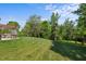 View of the back yard featuring a grassy lawn, mature trees, and a cozy pergola with outdoor seating at 1302 Ingle Ct, Burlington, NC 27215